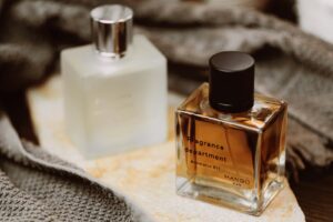 two bottles of cologne sitting on top of a blanket